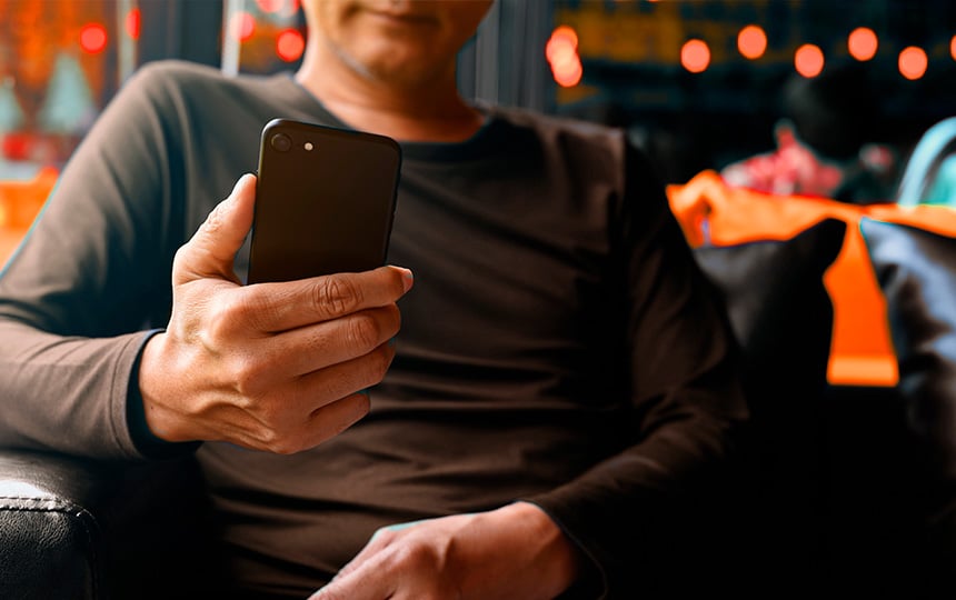 Imagem mostra um homem segurando um cartão de crédito com a mão esquerda, enquanto realiza uma compra online. A cena transmite a ideia de segurança em transações no ambiente virtual e como evitar chargeback no e-commerce.